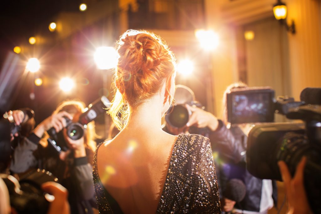 Celebrity being photographed by paparazzi photographers at event for the richest celebrities in the world