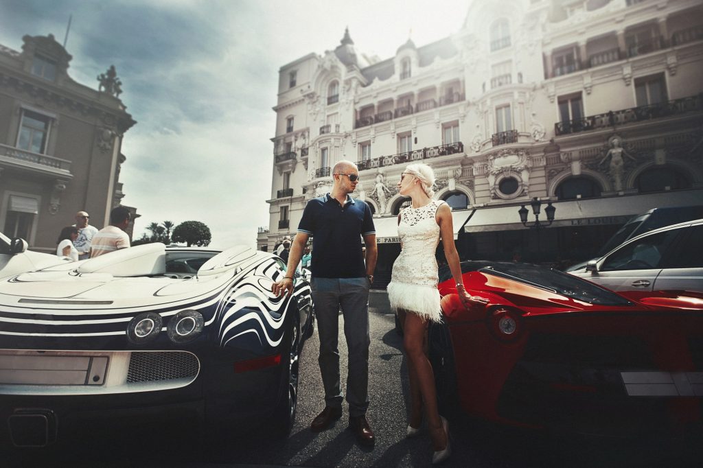 couple stands between sports cars expensive things in the world