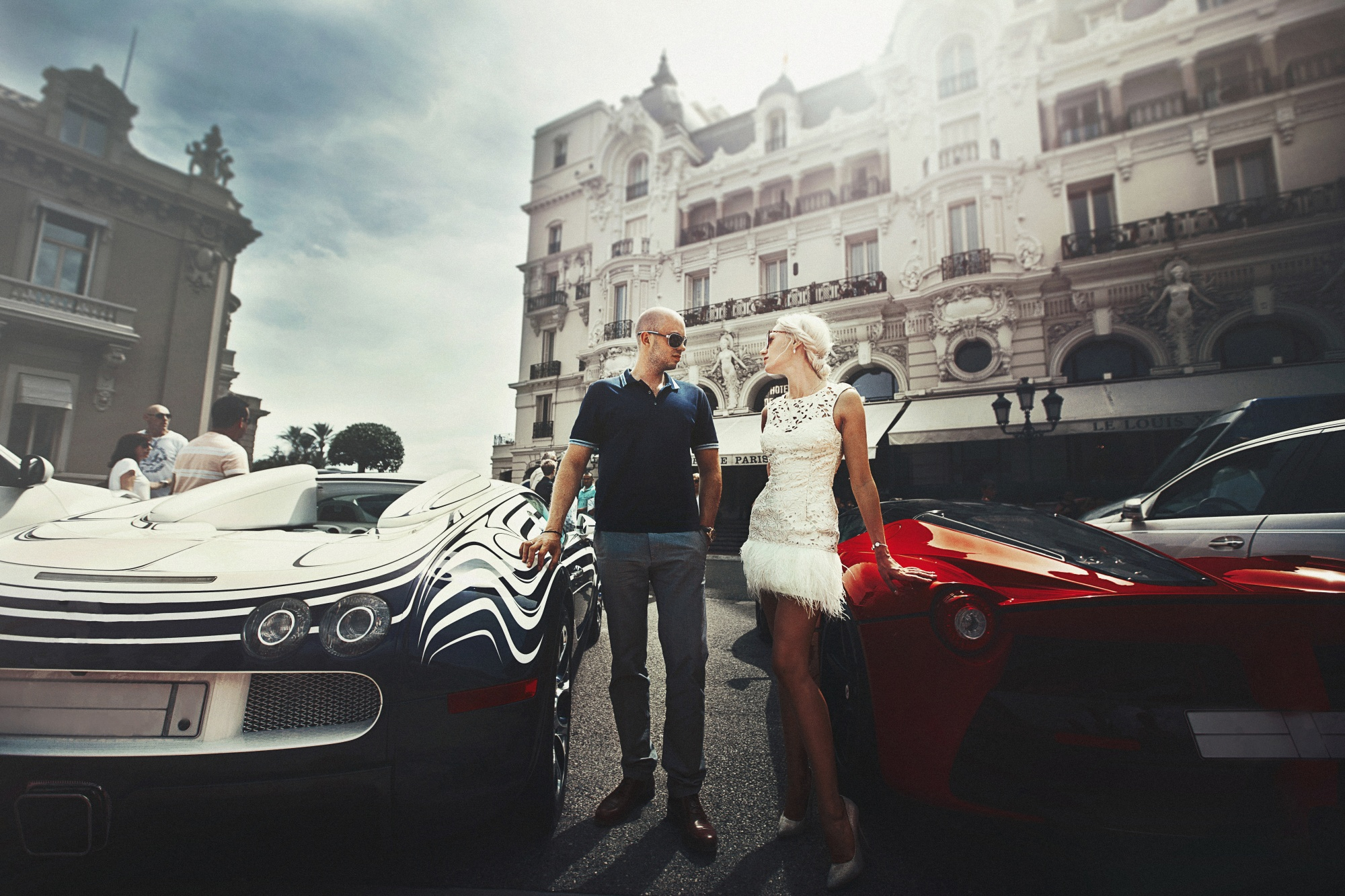 couple stands between sports cars