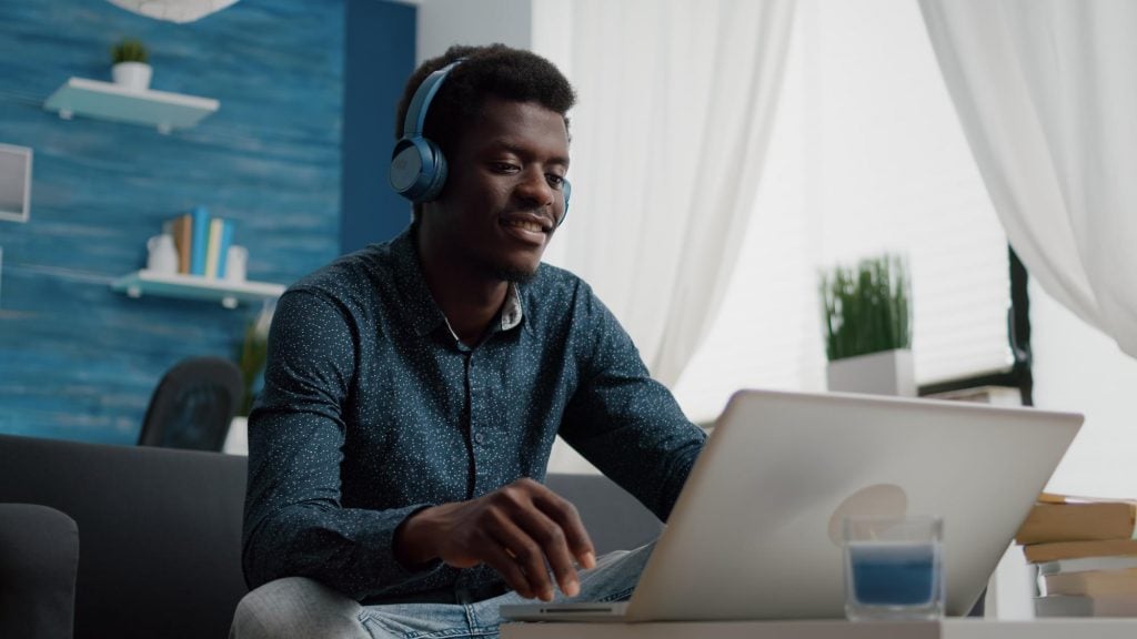 african american man with headphone listening to music while home office