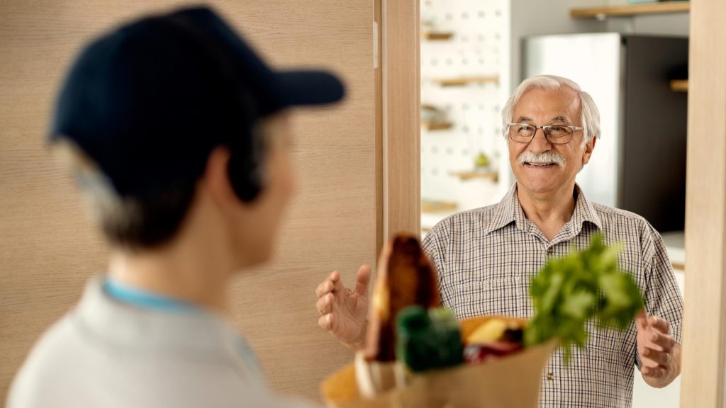 happy senior man receiving groceries delivery apps home