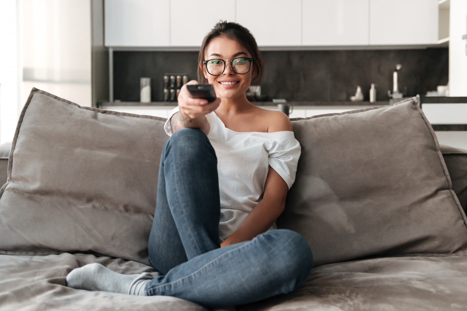 happy young woman sitting sofa home watching tv show