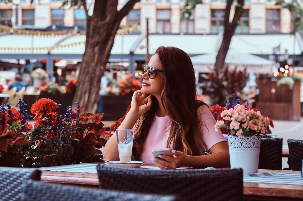 woman enjoying cafe with sunglasses holding cellphone safe city
