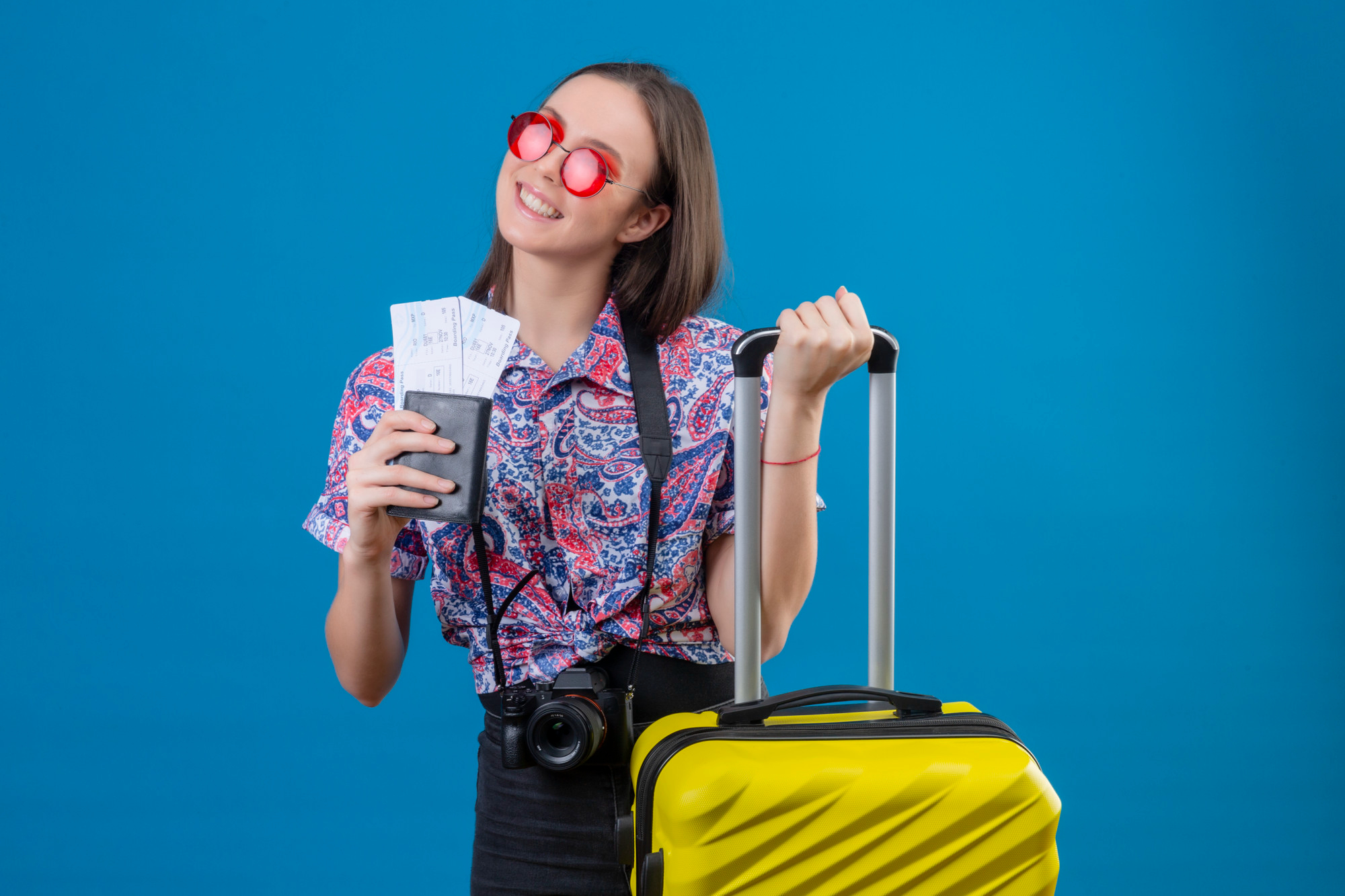 young traveler woman wearing red sunglasses with yellow suitcase holding passport and travel credit card