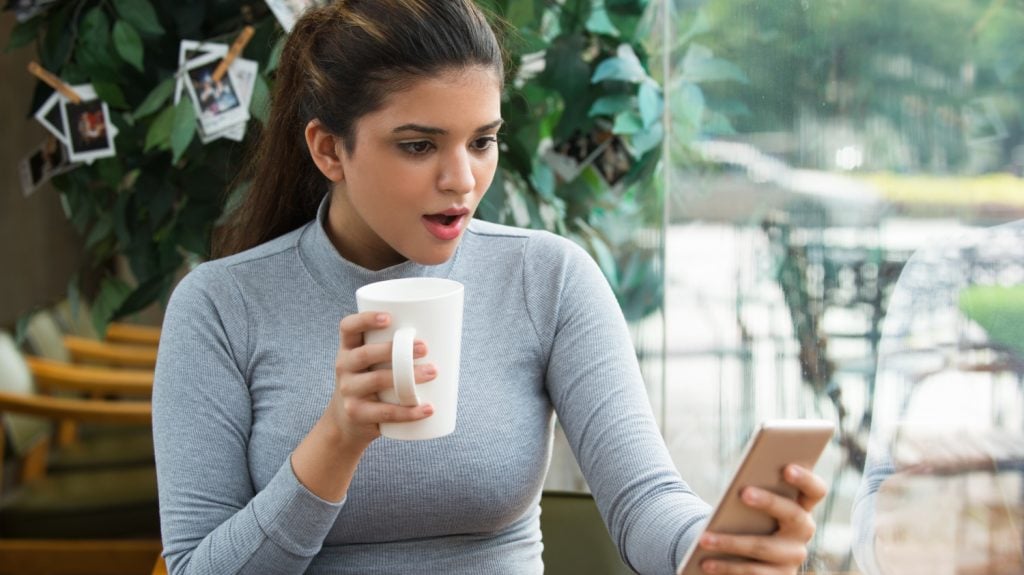 amazed girl drinking coffee using social media