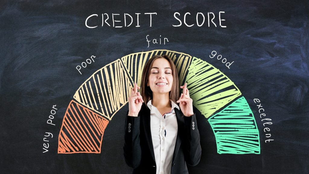 Bank loan concept with businesswoman crossing her fingers on blackboard background with credit score scale