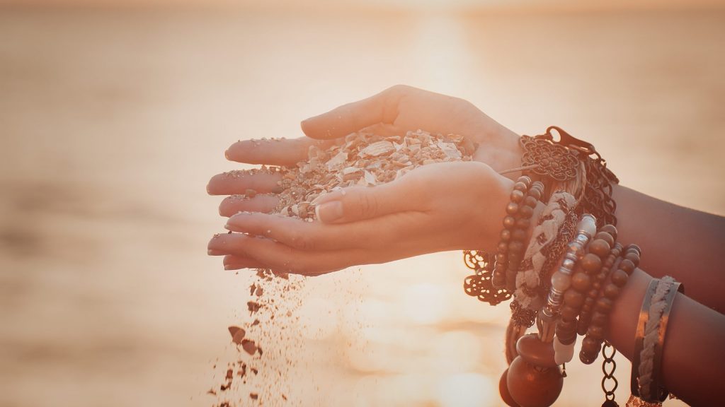 A woman with sand falling through her hands.summer background