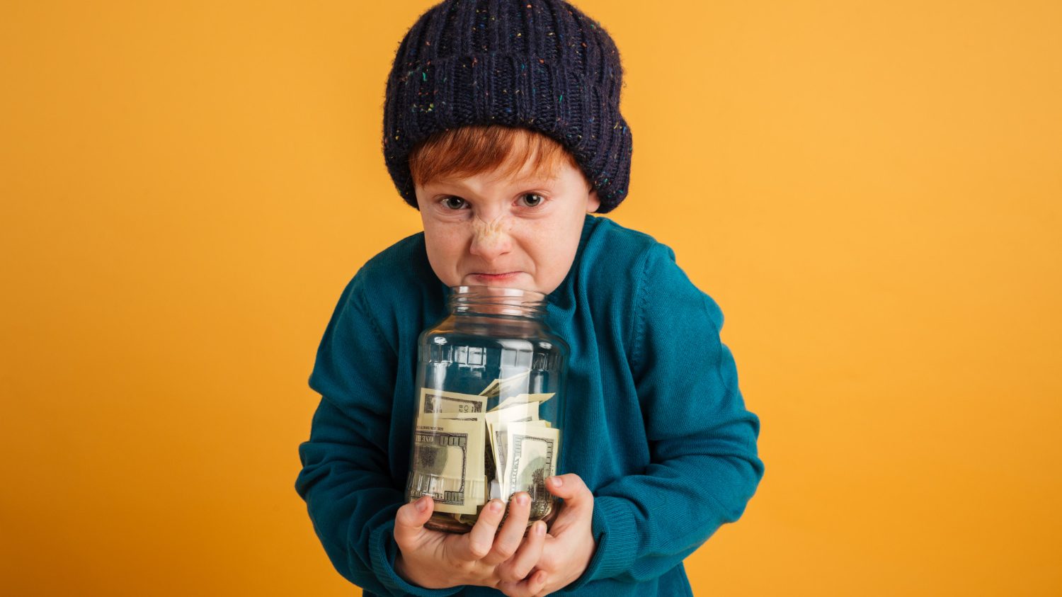 little boy holding jar full of money