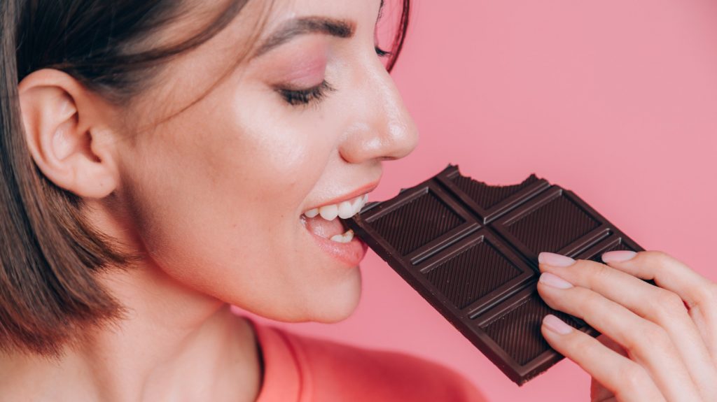 happy woman eating dark chocolate