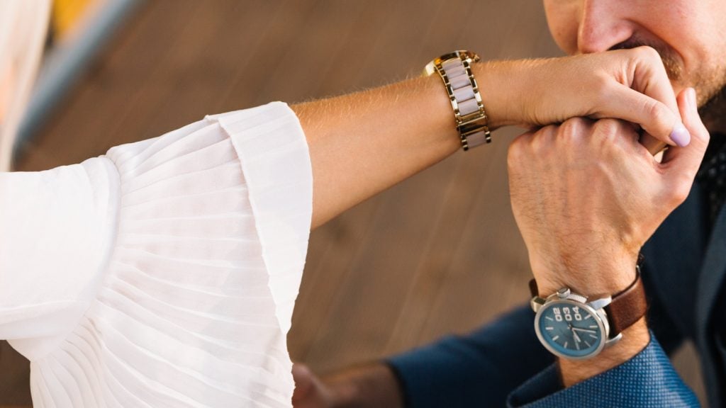 man kissing womans hand wearing watches