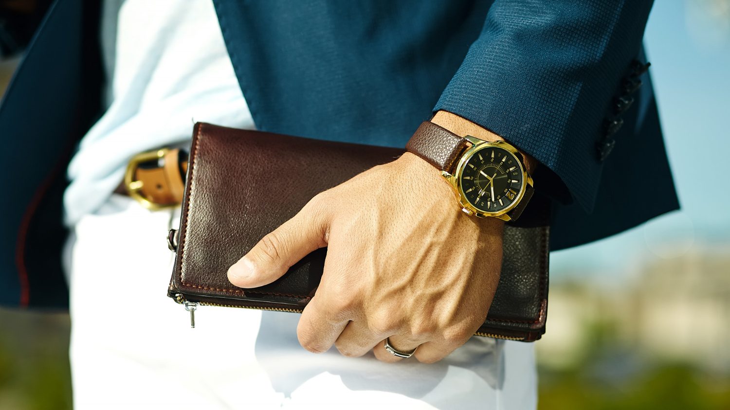 classy man holding leather wallet and watch