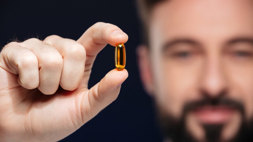 man holding vitamin B pill